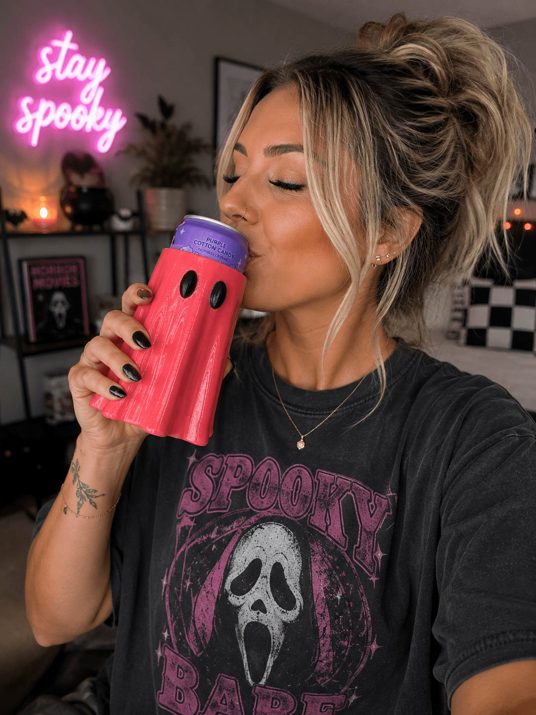 Woman drinking from white ghost-shaped 3D printed can holder with good vibes neon sign