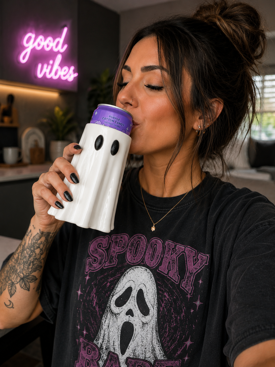 Woman drinking from pink ghost-shaped 3D printed can holder with stay spooky neon sign