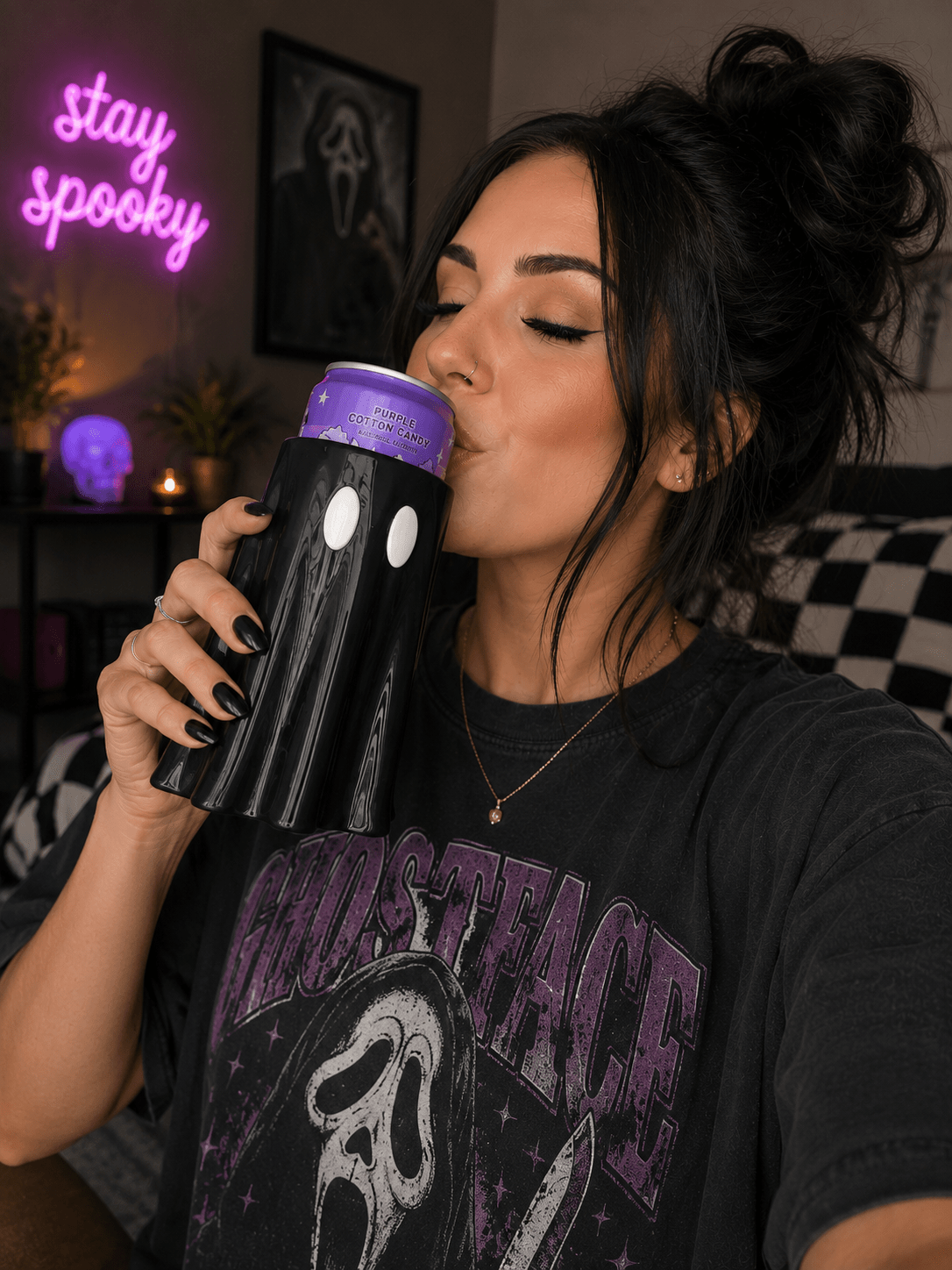 Woman drinking from black ghost-shaped 3D printed can holder with stay spooky neon sign