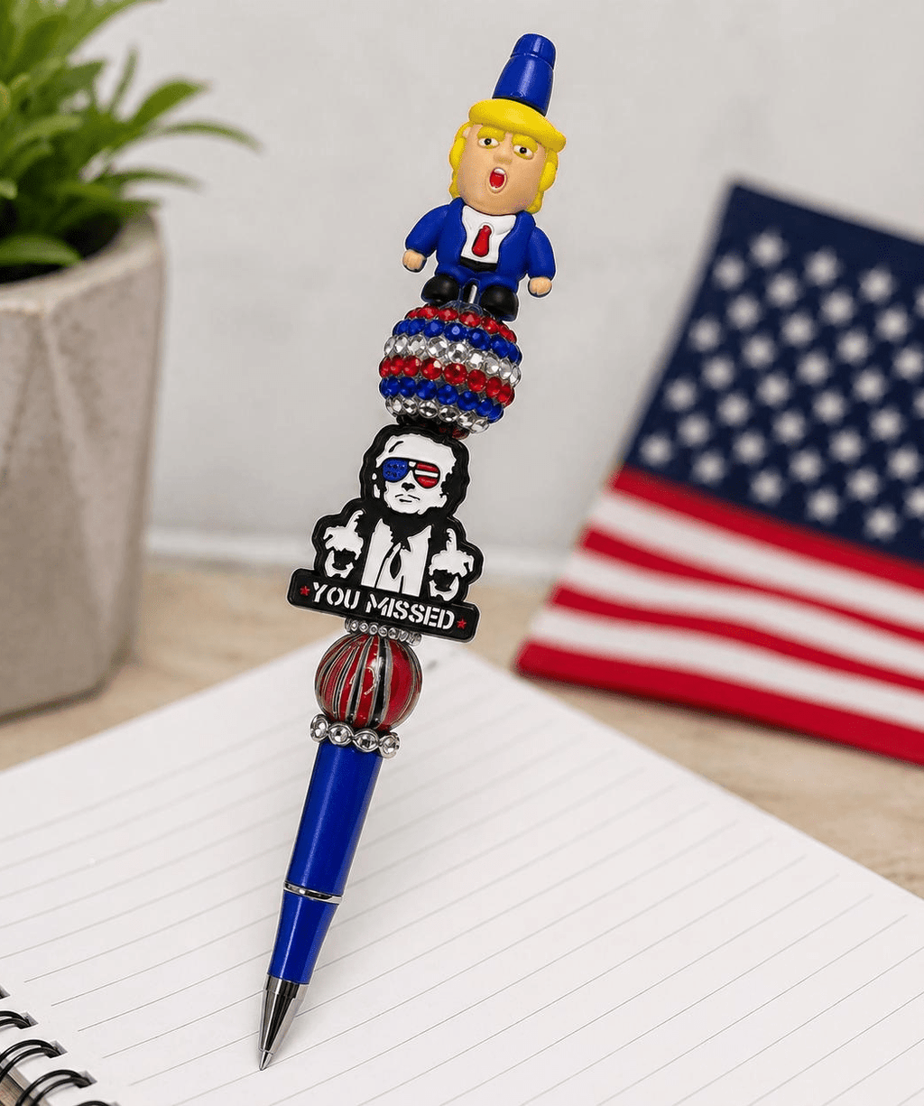 Patriotic beaded pen standing upright with political character topper, rhinestone disco ball, and You Missed charm