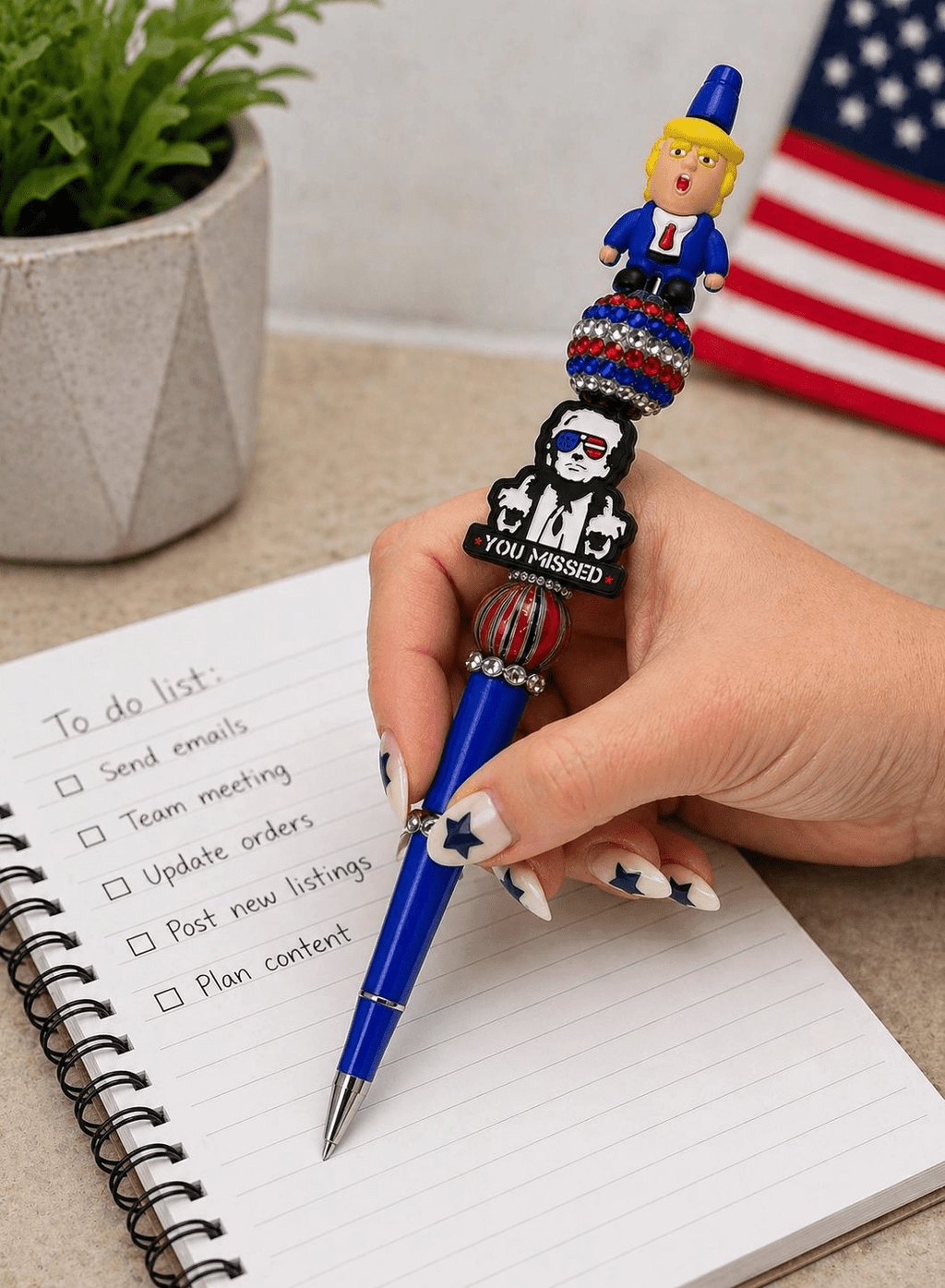 Hand holding patriotic beaded pen over a to-do list notebook